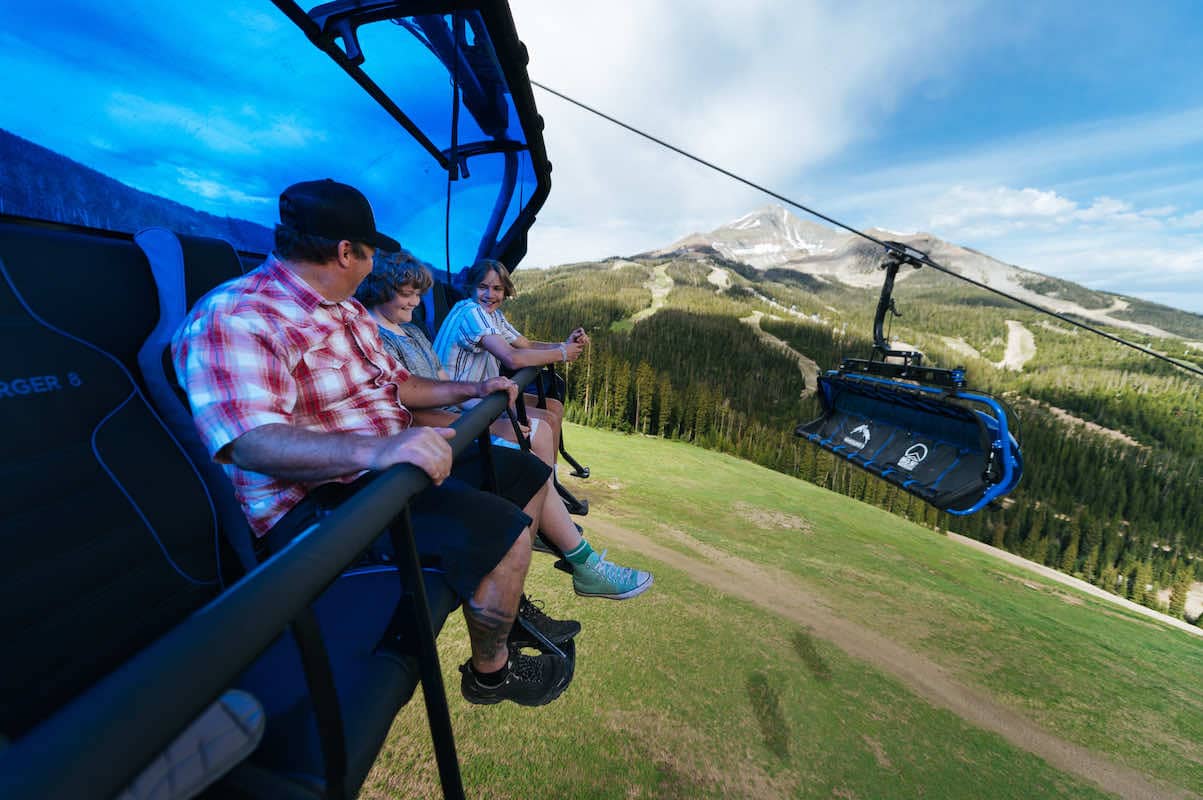 Father and two sons riding Ramcharger 8 on a scenic lift ride with Lone Peak in the background