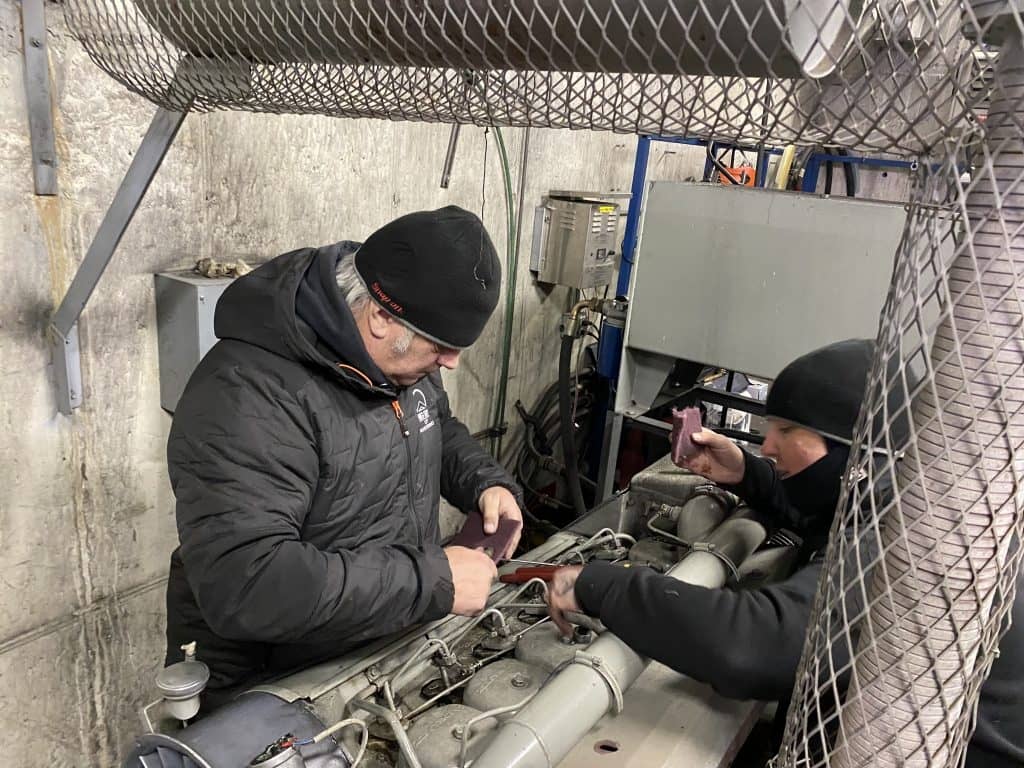 Two people working on an auxiliary engine