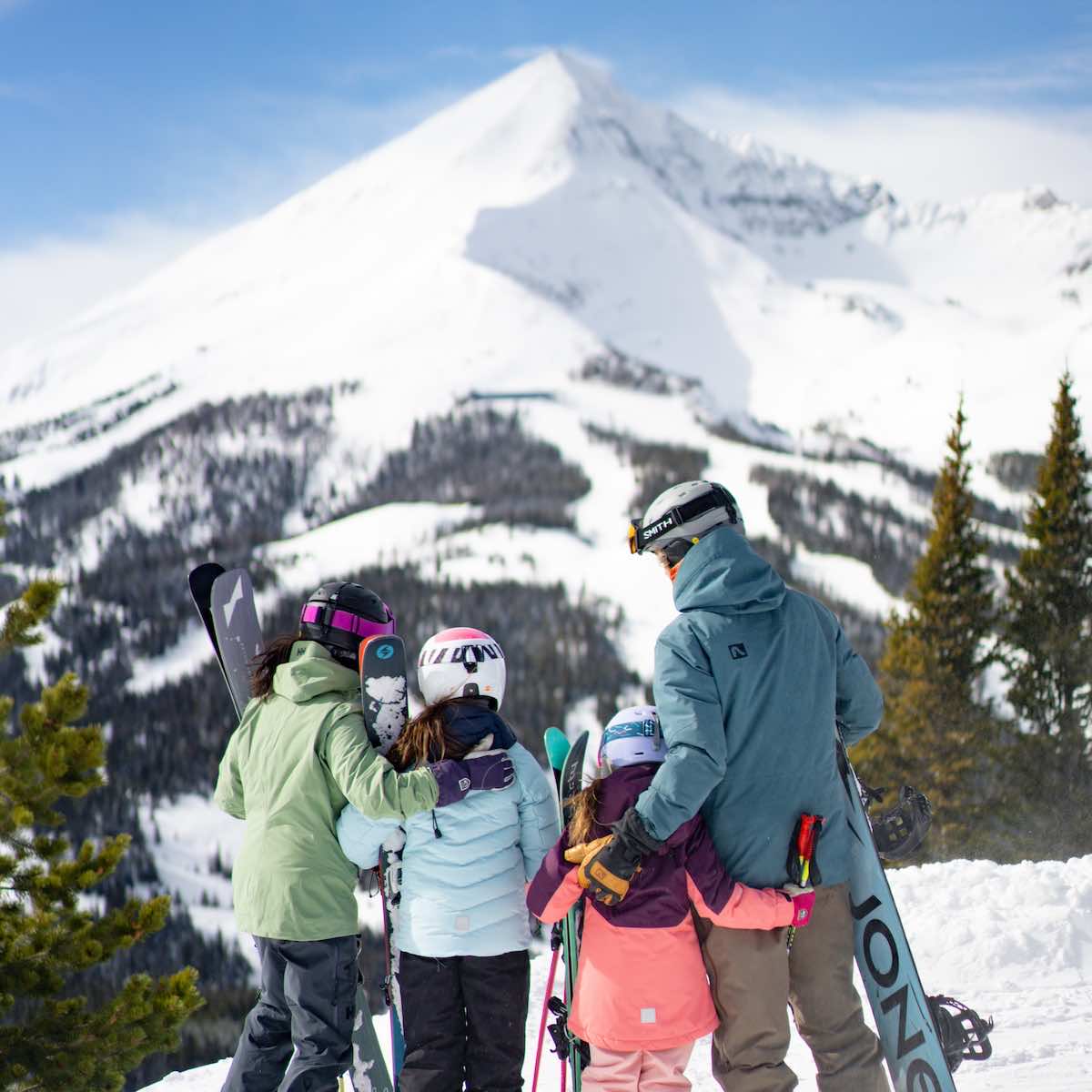 Family standing in ski gear with Lone Mountain in the background
