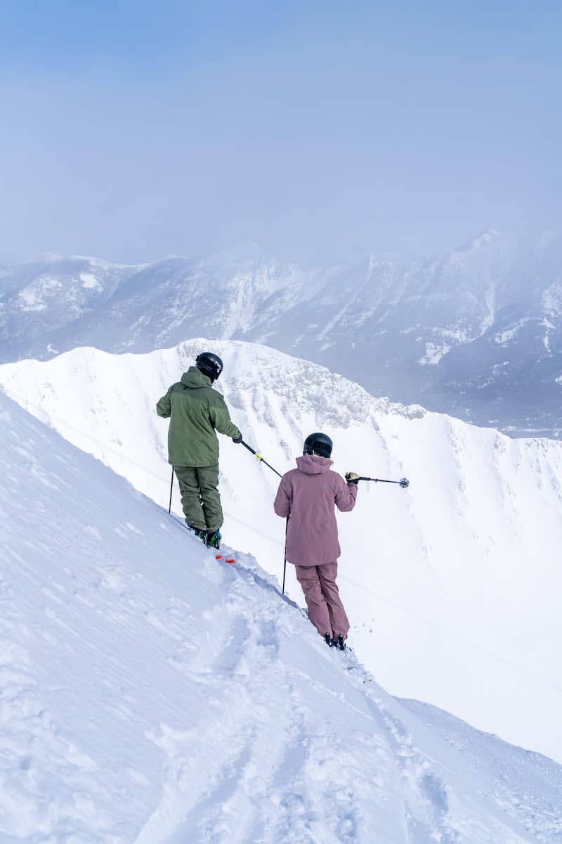 Skiers standing and pointing at a ridge